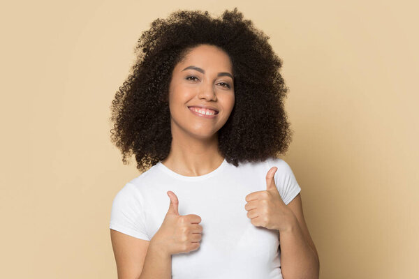 Красивая афроамериканская девушка со здоровой улыбкой показывает большие пальцы вверх
