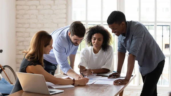Smiling mixed race colleagues explaining project ideas to female teammates. — Stock Photo, Image