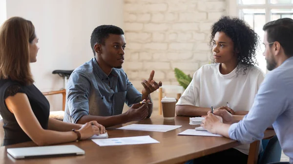 Afro-Amerikaanse jonge manager legt onderzoeksresultaten uit aan geconcentreerde teamgenoten. — Stockfoto