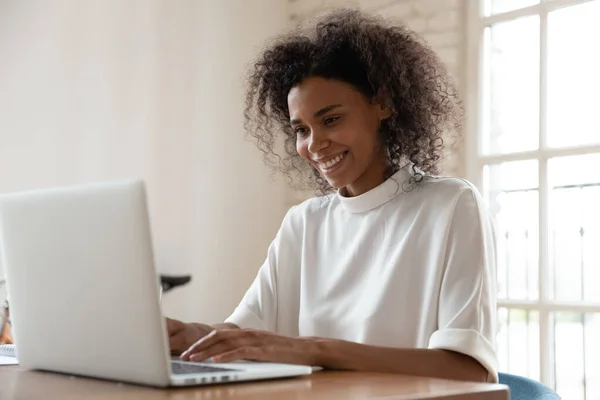 Afrikaans Amerikaans internationaal bedrijf werknemer zitten aan tafel met computer. — Stockfoto