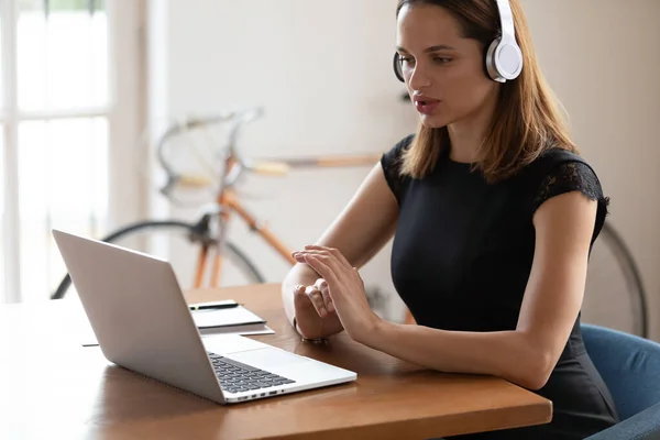 Concentrated businesswoman wearing wireless headphones, listening to educational seminar. — Stock Photo, Image