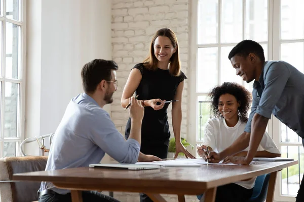 Sonrientes compañeros de equipo de raza mixta discutiendo ideas de proyectos en el lugar de trabajo . — Foto de Stock