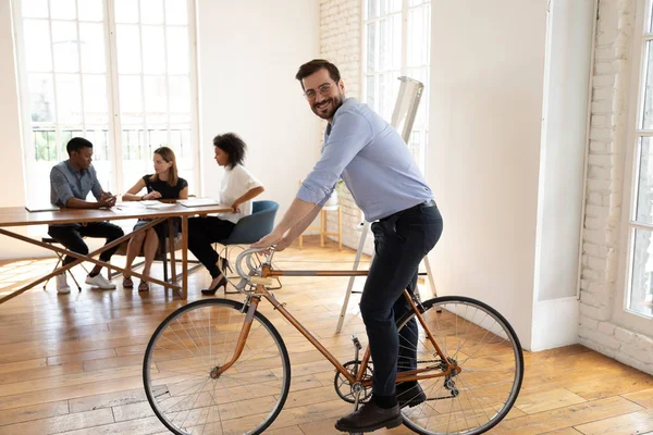Modern ofiste bisiklete binen neşeli genç işadamı..