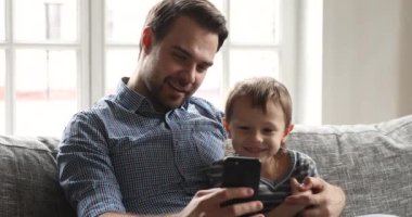 Mutlu baba çocuğuna evde akıllı telefon uygulamaları kullanmayı öğretiyor.