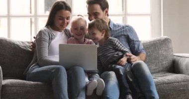 Sevimli komik çocuklar dizüstü bilgisayar kullanarak aileleriyle eğleniyorlar.
