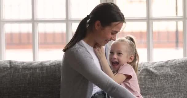 Alegre jovem mãe cócegas pequeno criança filha jogar no sofá — Vídeo de Stock