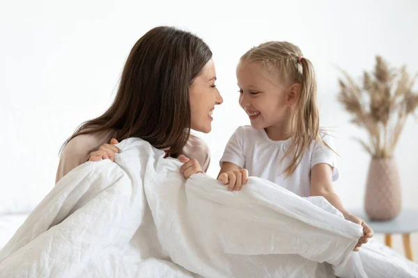 Niña preescolar jugando con feliz mami joven en el dormitorio . —  Fotos de Stock