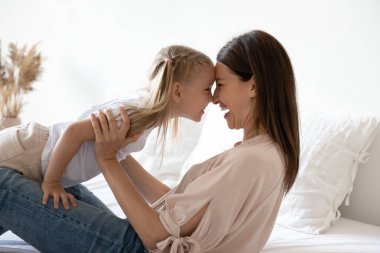 Mutlu anne yatakta neşeli küçük tatlı kızıyla oynuyor..