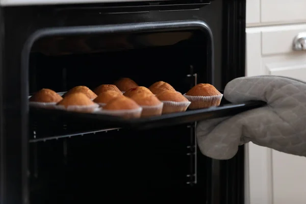 Žena v domácnosti nebo profesionální cukrář brát chutné muffiny z trouby. — Stock fotografie