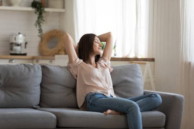 Modern oturma odasındaki kanepede uzanan mutlu genç kadın..