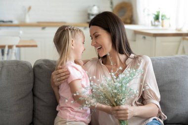 Happy 30s woman feeling thankful to daughter for prepared flowers. clipart