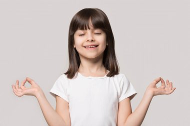 Meditasyon yapan küçük kahverengi saçlı kızın portresini yakından çek..