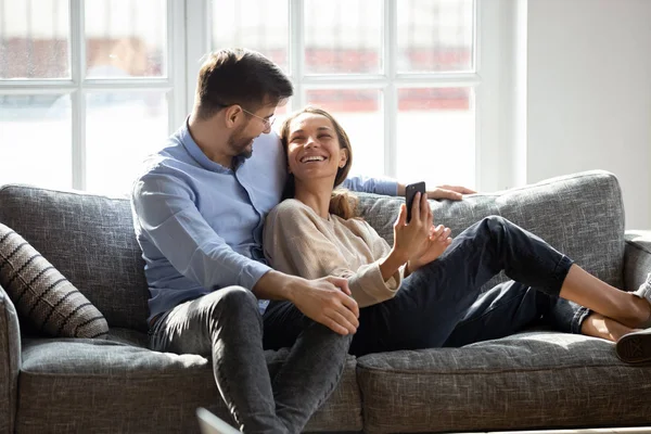 Laughing millennial mixed race woman showing funny video to husband. — Stock Photo, Image