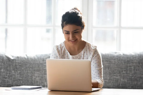 Sourire jeune femme indienne travaillant à distance sur ordinateur à la maison . — Photo