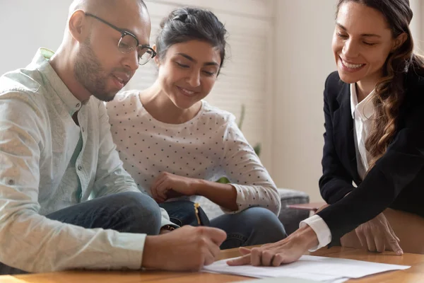 Happy young indian woman watching african american husband signing contract. — Stock Photo, Image