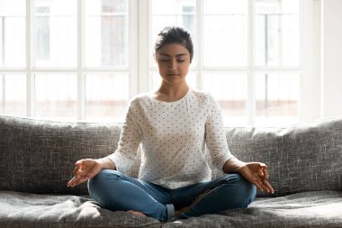 Dikkatli genç Hintli kadın tek başına yoga egzersizleri yapıyor..