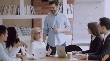 Mutlu erkek koç çeşitli takımlarla konuşuyor. Toplantı odasında şakalaşıyorlar.