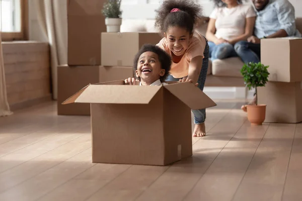 Sister riding younger brother who is sitting in cardboard box — Stock Photo, Image