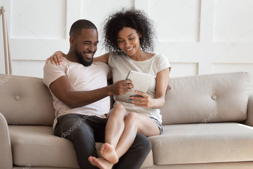 Happy biracial couple watch video on laptop at home together