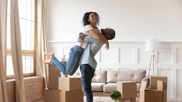 Marido africano levantando esposa feliz familia celebrando día de reubicación — Foto de Stock