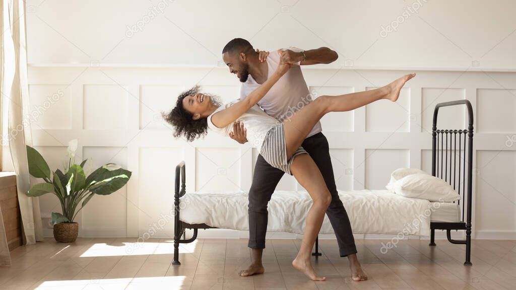 Happy african American couple dancing together in bedroom