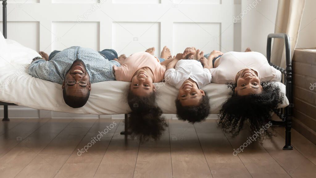 African family lies on bed heads down looking at camera