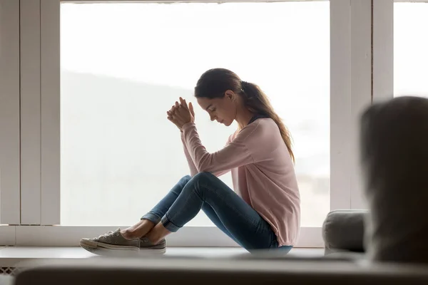 Unhappy young woman sit on windowsill thinking — Stock Photo, Image