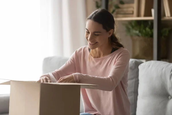 Feliz cliente femenino paquete de cartón abierto en casa —  Fotos de Stock