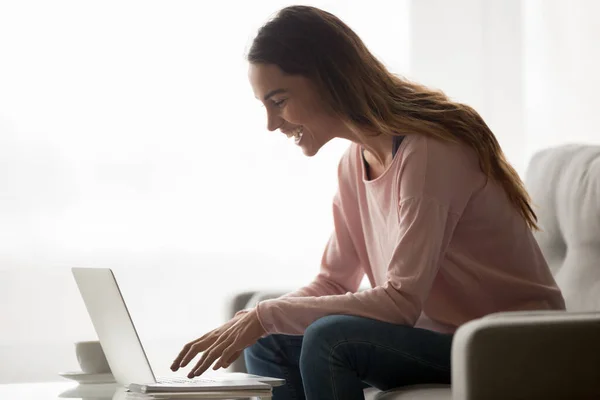 Chica feliz risa usando mensajería portátil en casa — Foto de Stock