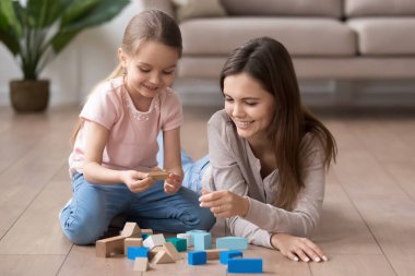 Gülümseyen anne ve küçük kız oyuncak bloklarıyla oynuyorlar.