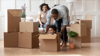 Afrikalı bir baba, küçük oğlunu kutunun içinde oturtuyor.