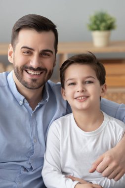 Mutlu bir baba, gülümseyen bir oğlana sarılıyor.