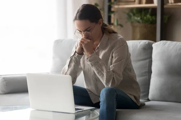 Mulher pensativa olha para o laptop pensando na solução do problema — Fotografia de Stock