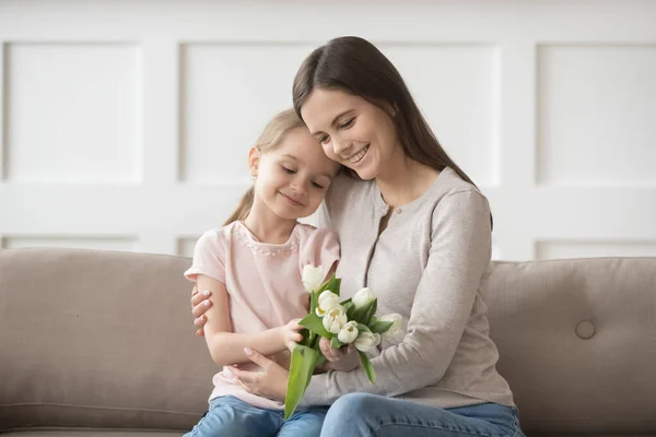 Lycklig mamma kram liten dotter tacka för presenterade blommor — Stockfoto