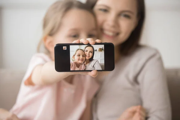 Усміхаючись молода мама і маленька дочка роблять мобільний телефон селфі разом — стокове фото