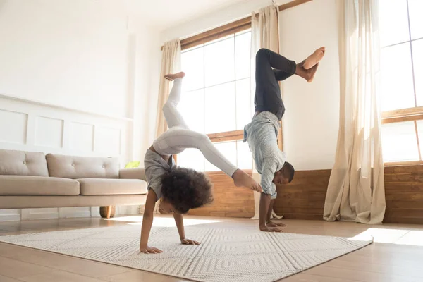Active biracial dad and daughter exercise at home together — ストック写真
