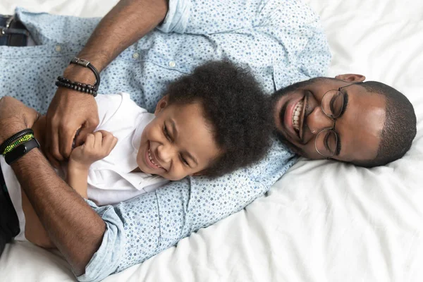 Top view loving father tickles little son lying on bed — Stock Photo, Image