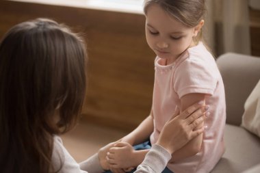 Anne, kanepede oturan mutsuz anaokulu kızına dokun.