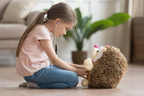 Cute little girl play doctor game with toy hedgehog — Stock Photo, Image