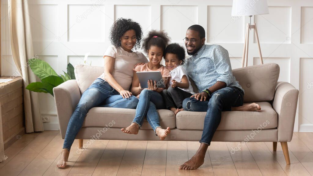 African full family using tablet computer resting on couch