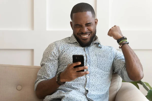 Happy african American man get good news on smartphone — Stock Photo, Image