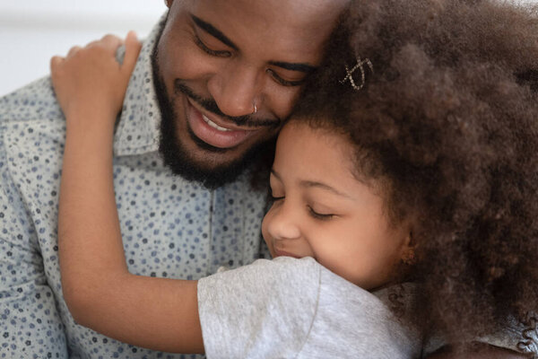 Loving african American dad hug little daughter