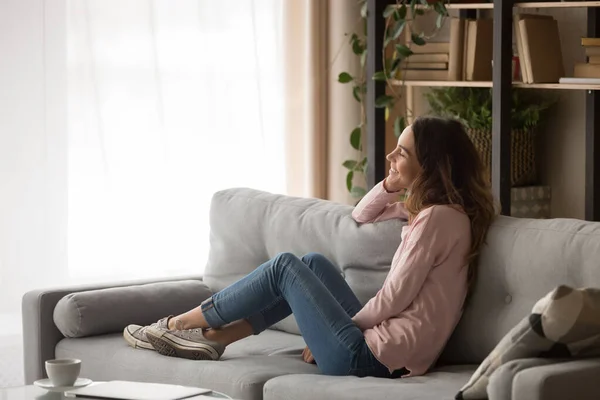 Sorrindo jovem mulher relaxar no sofá sonhando — Fotografia de Stock