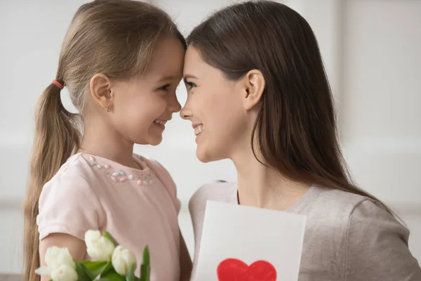 Cute little girl present flowers and postcard for young mom