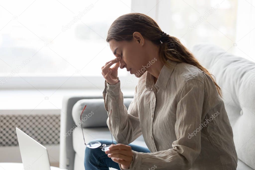Tired young woman massaging eyes suffering from headache