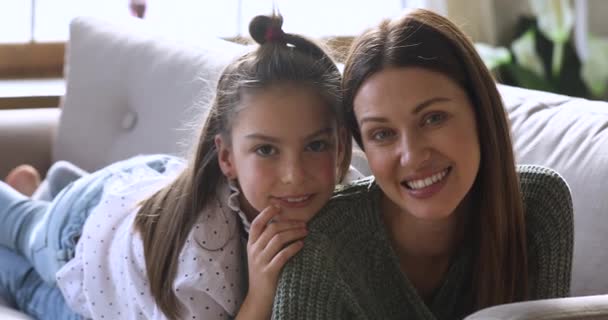 Daughter embracing mum lying on her back looking at camera — Stock Video