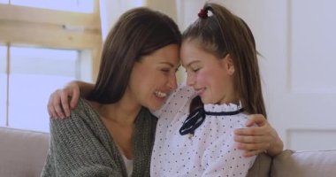 Güzel kız annesini kucaklıyor. Kanepeye oturup kameraya bakıyor.