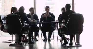 Kendine güvenen işadamı konferans masasında çeşitli iş adamlarıyla konuşuyor.