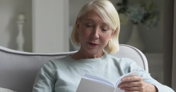 Happy volwassen dame lezen boek ontspannen op bank thuis — Stockvideo