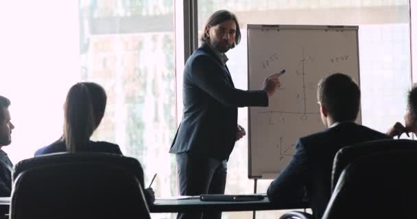 Businessman coach presenting financial strategy on flip chart at meeting — Stock Video